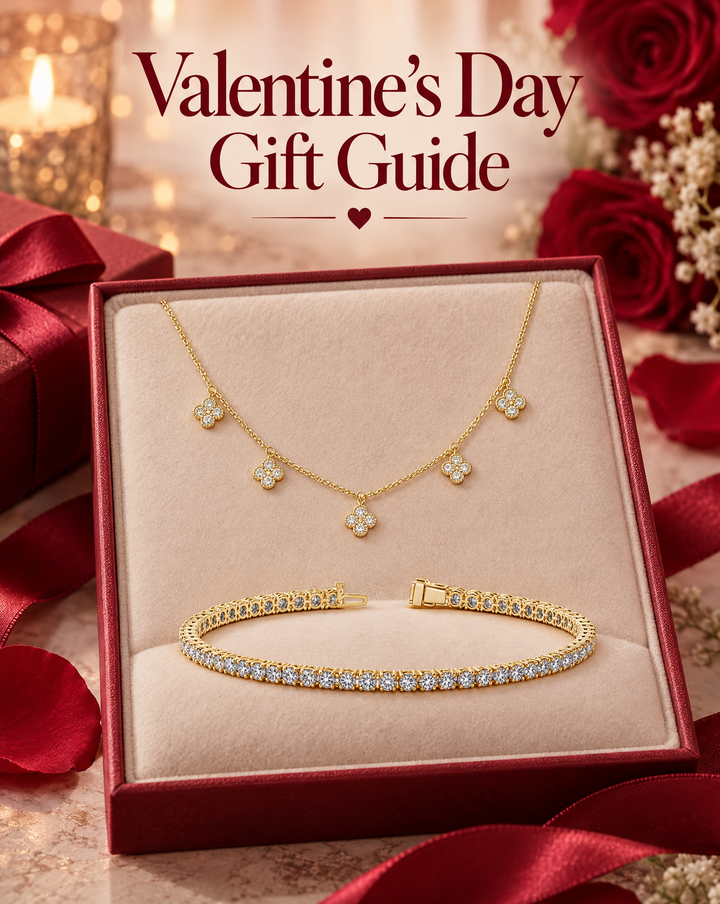 A yellow gold diamond flower necklace and a diamond tennis bracelet in an open gift box with red roses and candlelight, under the words Valentine’s Day Gift Guide