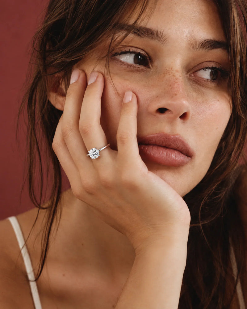 Engagement rings: 2 carat round lab-grown diamond solitaire ring in 14K white gold worn on the hand — AI-generated image — DEEVE