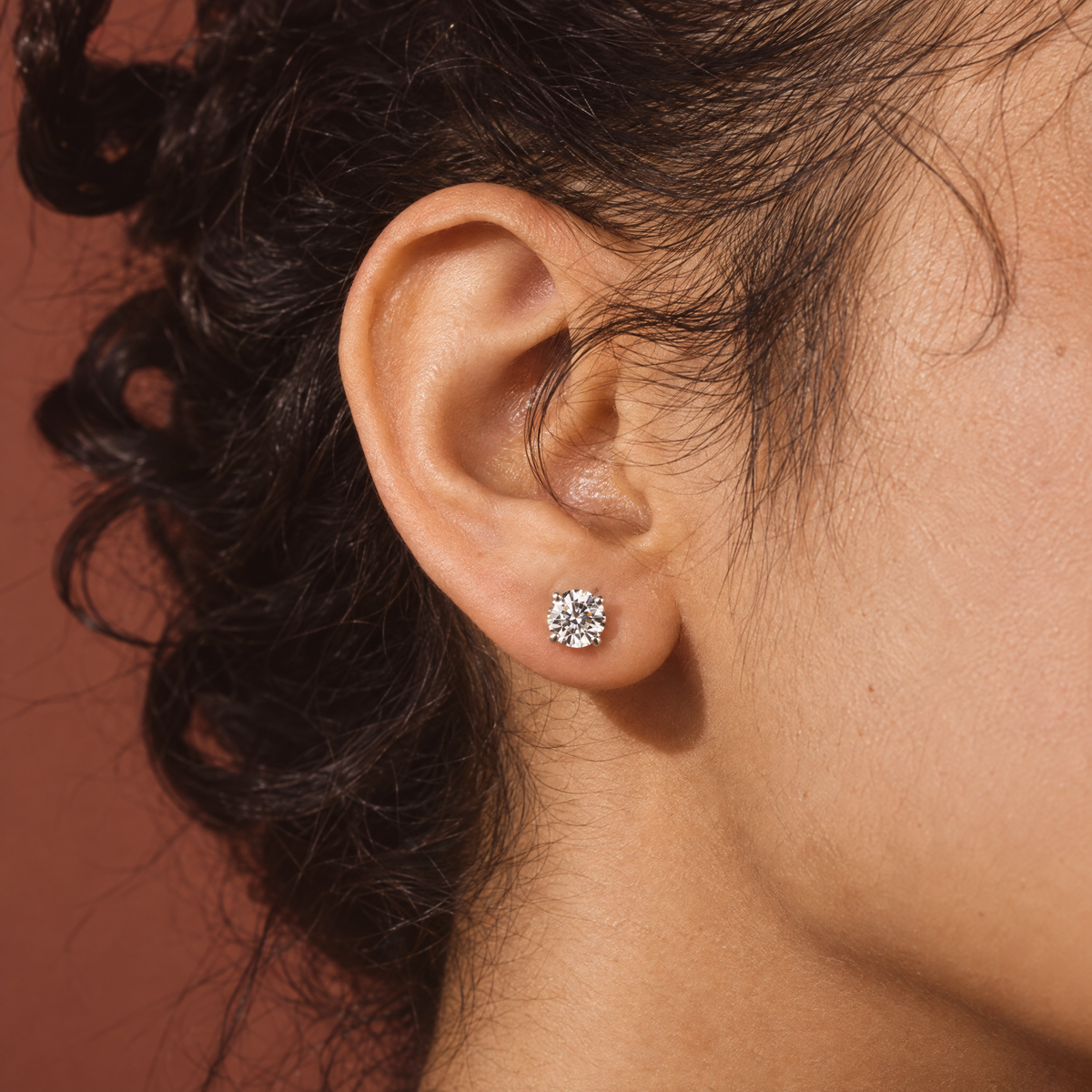 Close-up of one of a pair of 1 carat lab-grown diamond stud earrings in 14K white gold, worn on the ear, AI-generated image — DEEVE