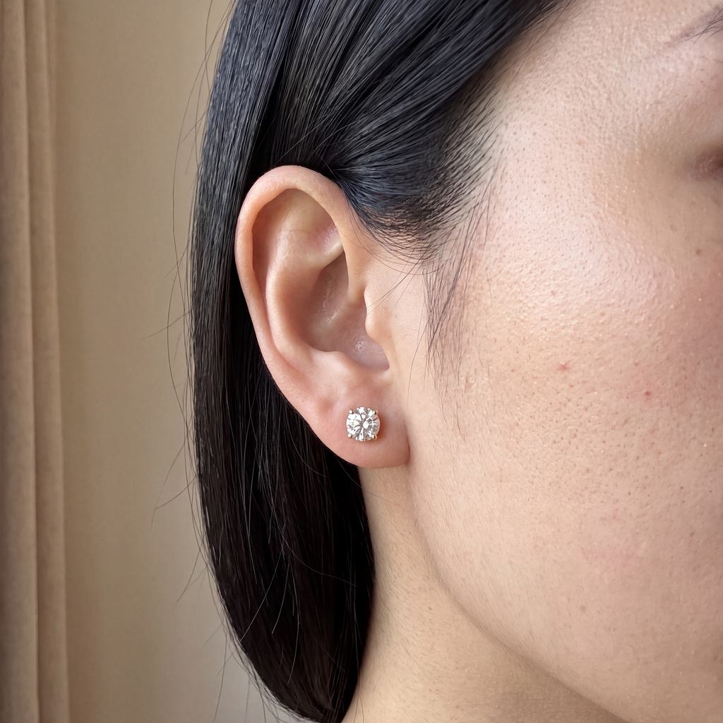 Candid-style close-up of one of a pair of 2 carat lab-grown diamond stud earrings in 14K yellow gold, worn on the ear, AI-generated image — DEEVE