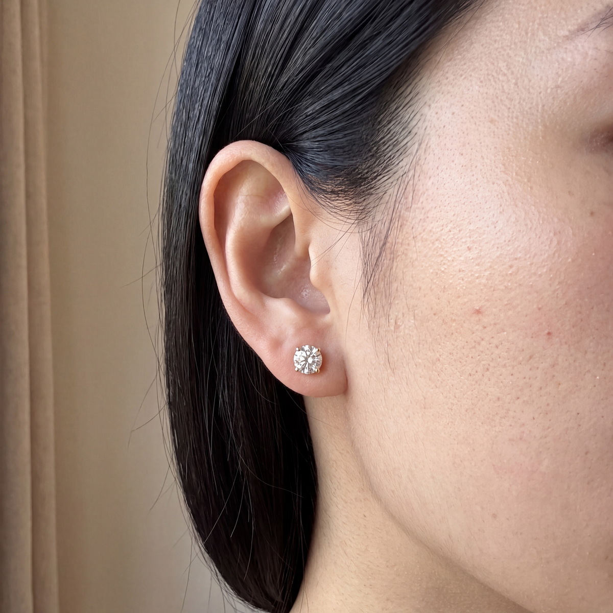 Candid-style close-up of one of a pair of 2 carat lab-grown diamond stud earrings in 14K yellow gold, worn on the ear, AI-generated image — DEEVE
