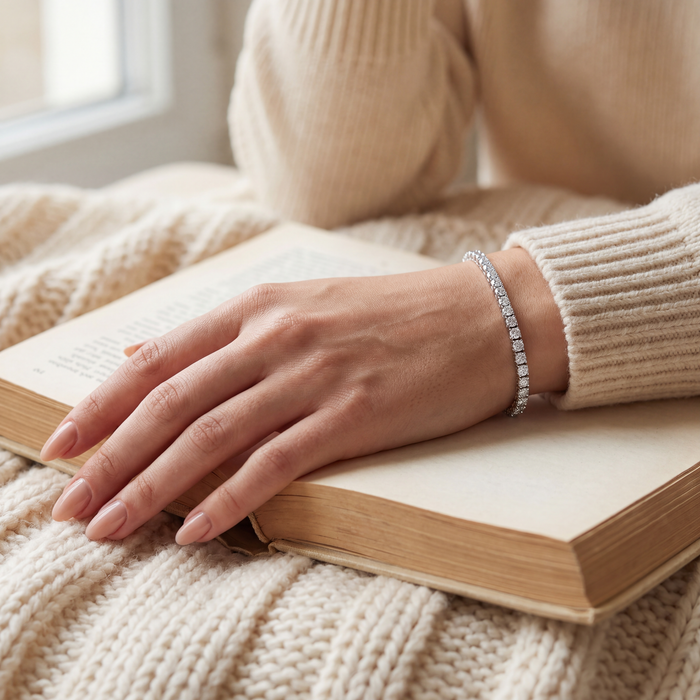 4 carat lab-grown diamond tennis bracelet in 14K white gold worn on the wrist, hand resting on an open book, AI-generated image — DEEVE
