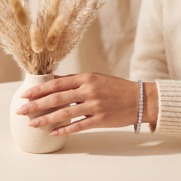 7 carat lab-grown diamond tennis bracelet in 14K white gold worn on the wrist, hand beside a ceramic vase, AI-generated image — DEEVE