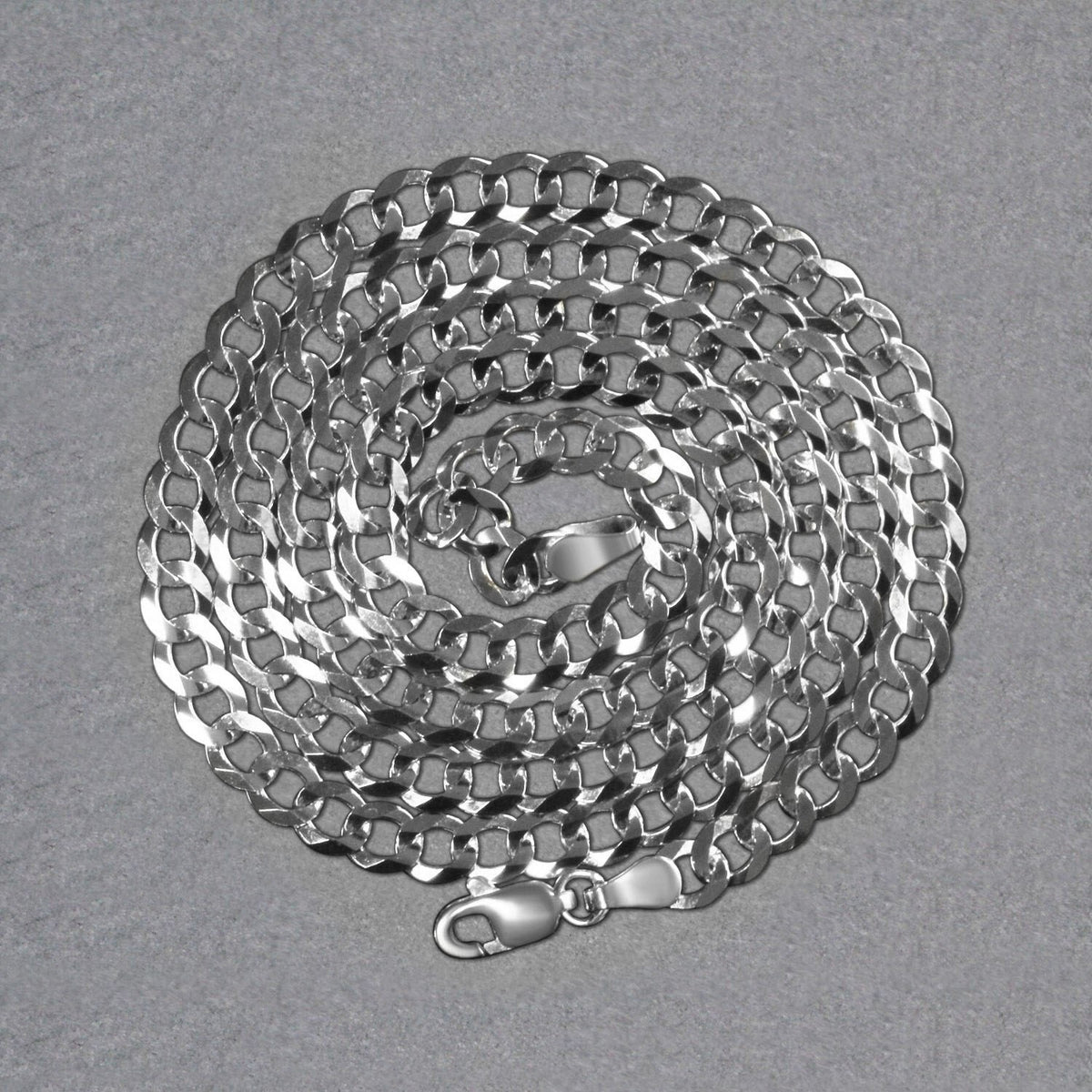 14K white gold curb chain, 4.70mm, coiled on a dark surface