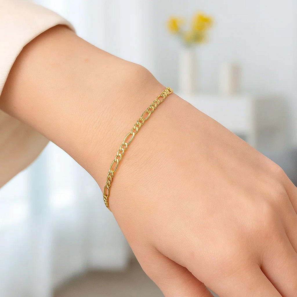 Fine Figaro bracelet in 14K yellow gold worn on a woman's wrist