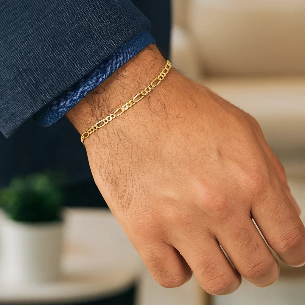 Figaro bracelet in 14K yellow gold worn with a navy jacket cuff