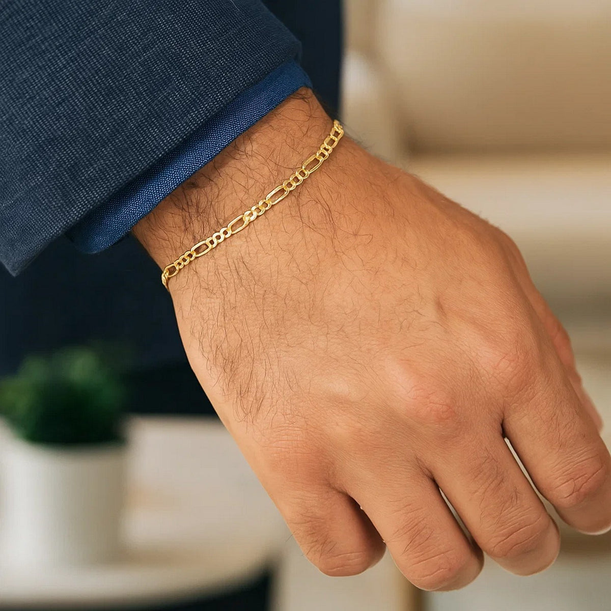 Figaro bracelet in 14K yellow gold worn with a navy jacket cuff