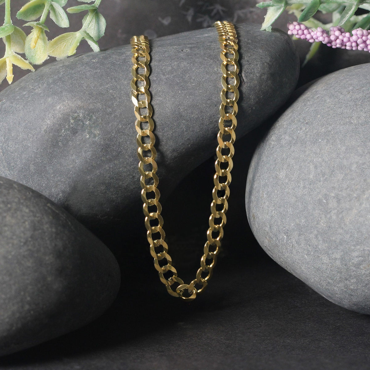 Curb chain in 14K yellow gold draped over two stones
