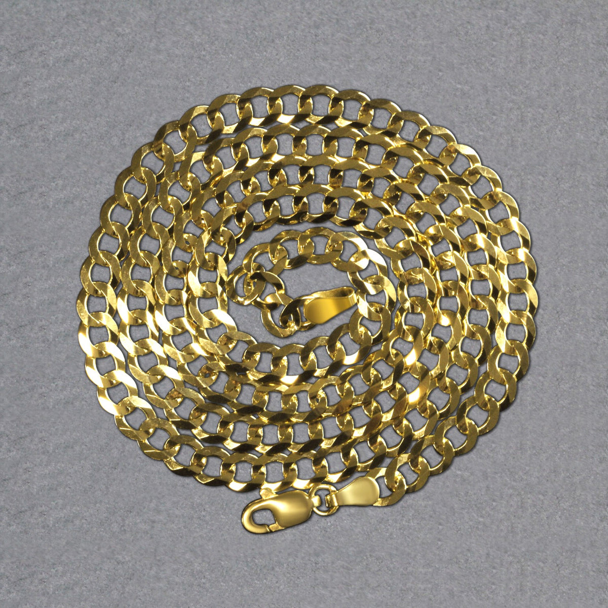 14K yellow gold curb chain, 4.70mm, coiled on a dark surface