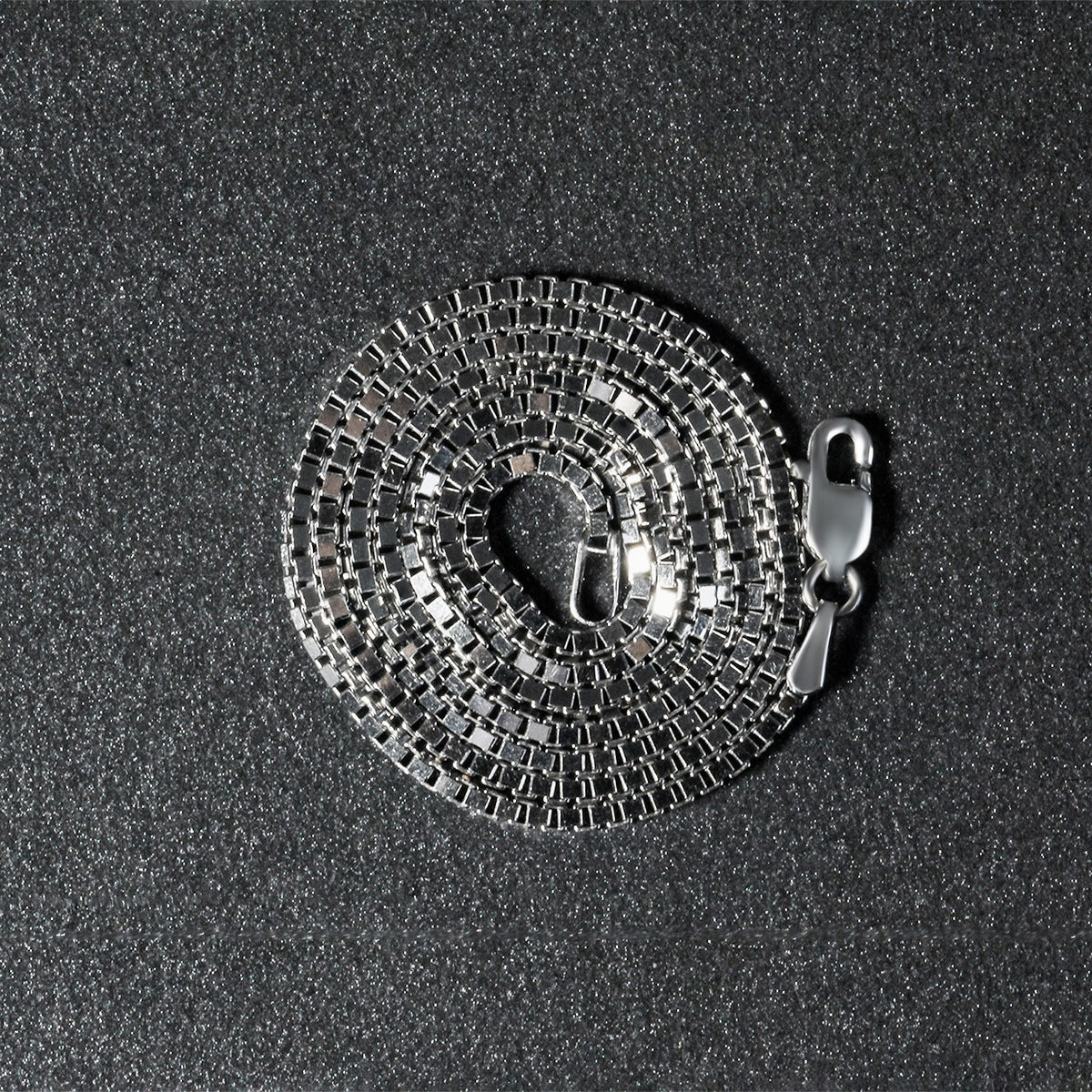 14K white gold box chain, 1.4mm, coiled on a dark surface