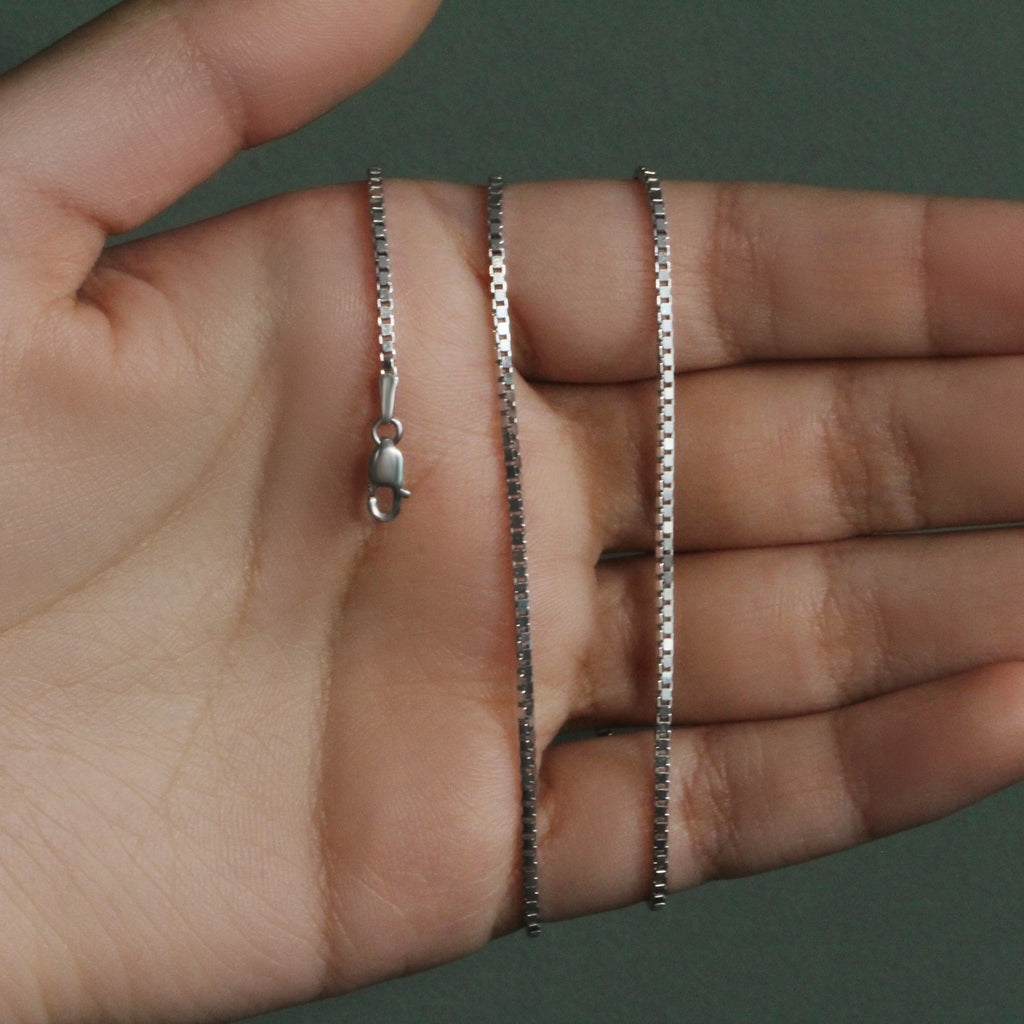 1.4mm box chain in 14K white gold held across an open palm