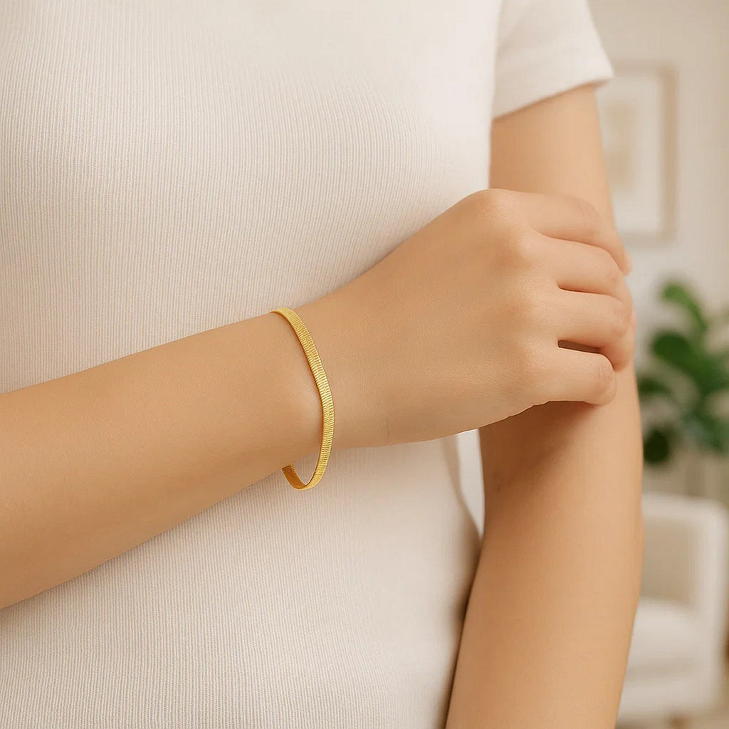 Herringbone bracelet in 14K yellow gold worn with a white top