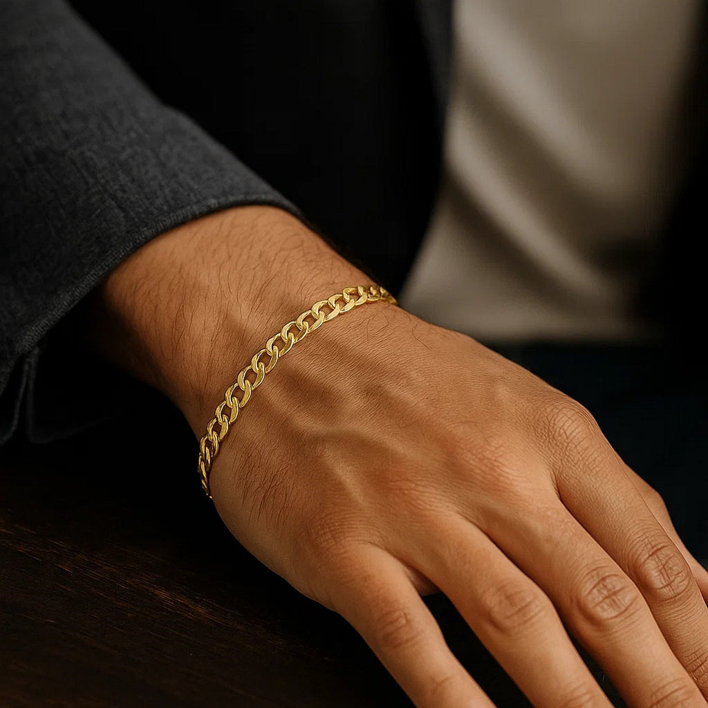 Curb bracelet in 14K yellow gold on a man's hand resting on dark wood