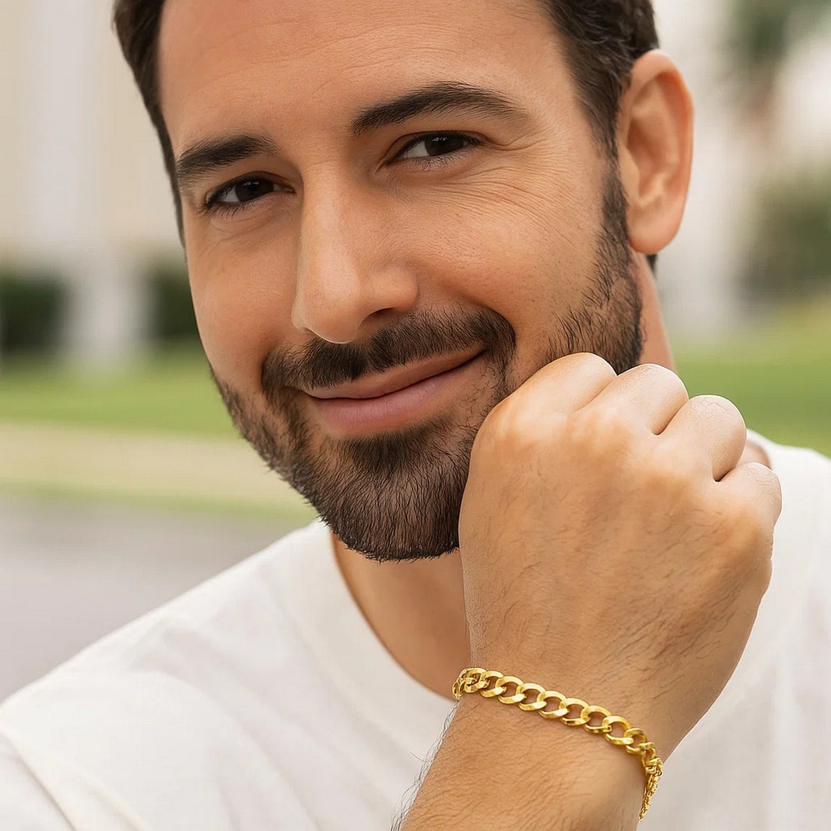 Man in a white tee outdoors wearing a yellow gold curb bracelet
