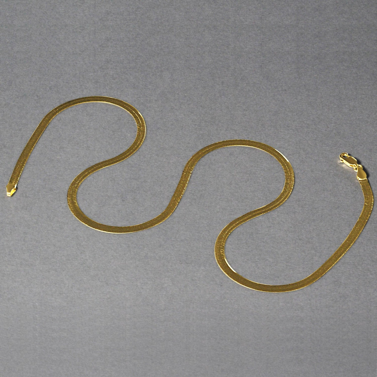 Herringbone chain in 14K yellow gold laid out in loops
