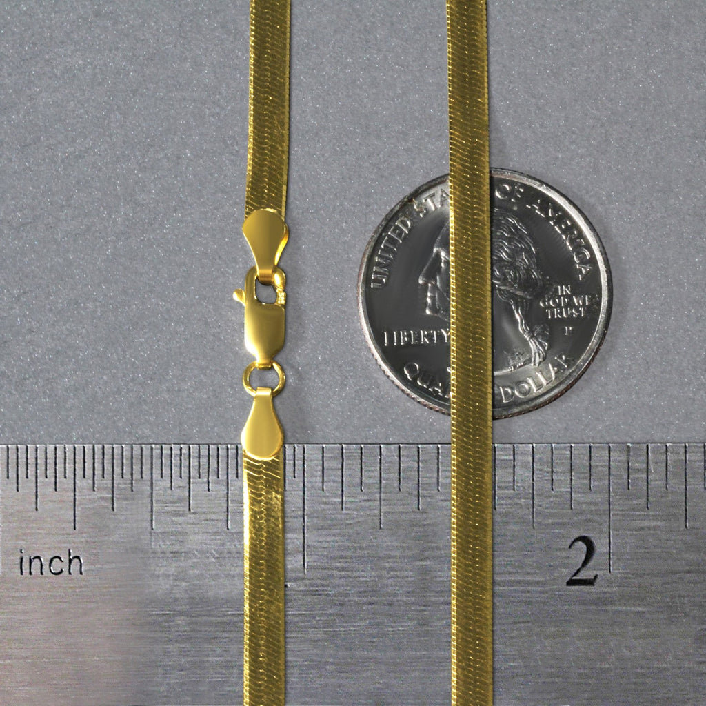 3.80mm herringbone chain in 14K yellow gold beside an inch ruler and a coin for scale