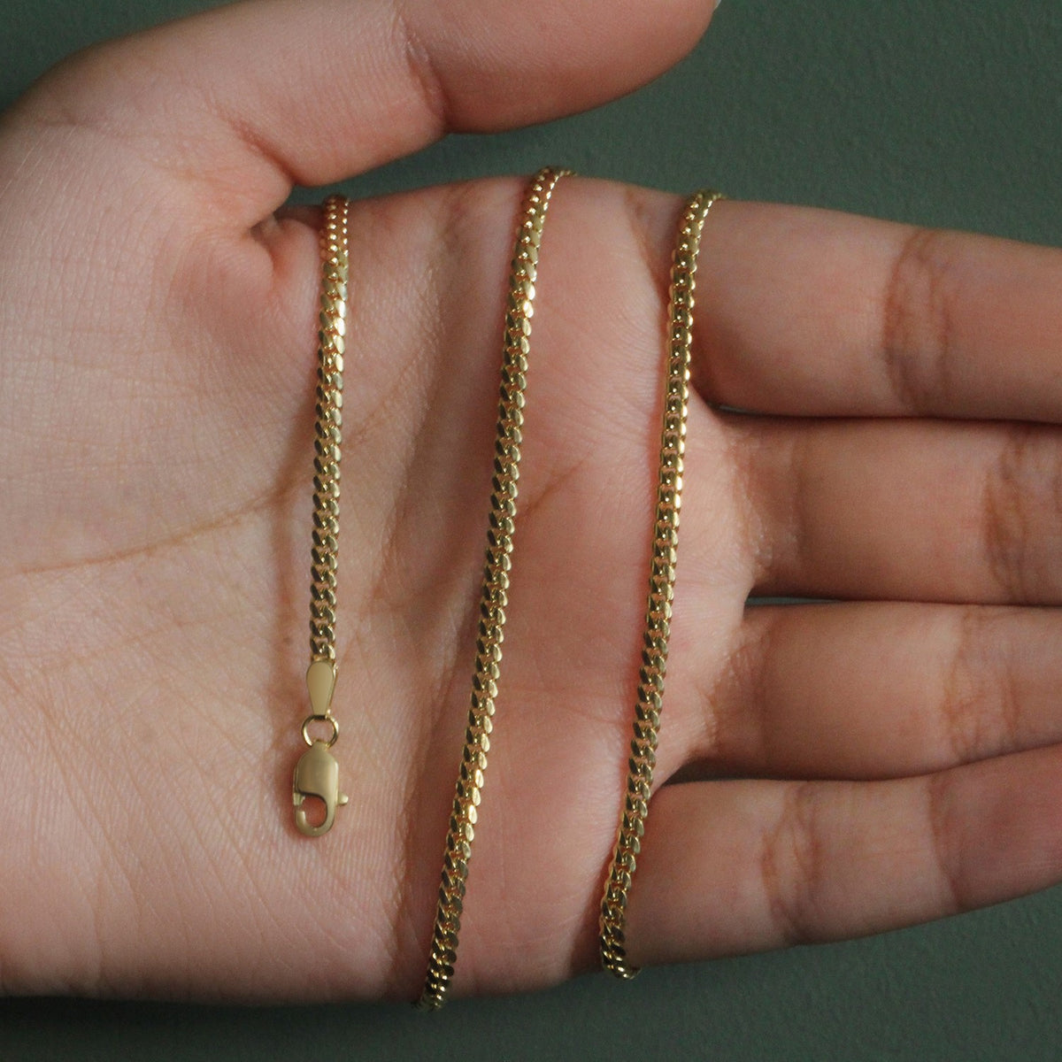 2.60mm solid Miami Cuban chain in 14K yellow gold held across an open palm