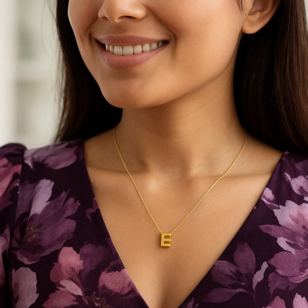 Block letter E initial necklace in 14K yellow gold worn at the neckline