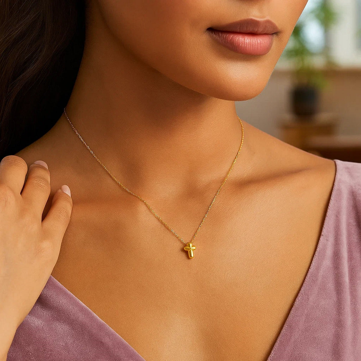 Puffed mini cross necklace in 14K yellow gold worn at the collarbone with a mauve velvet top