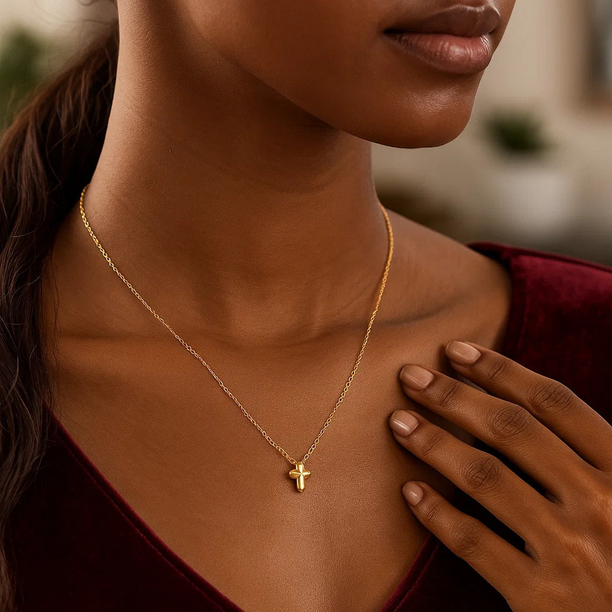 Puffed mini cross necklace worn with a burgundy velvet V-neck