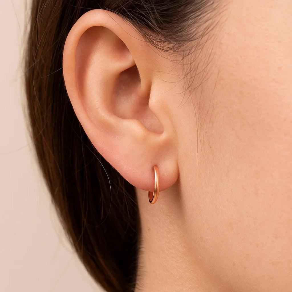 Close-up of a petite 14K rose gold hoop on the ear