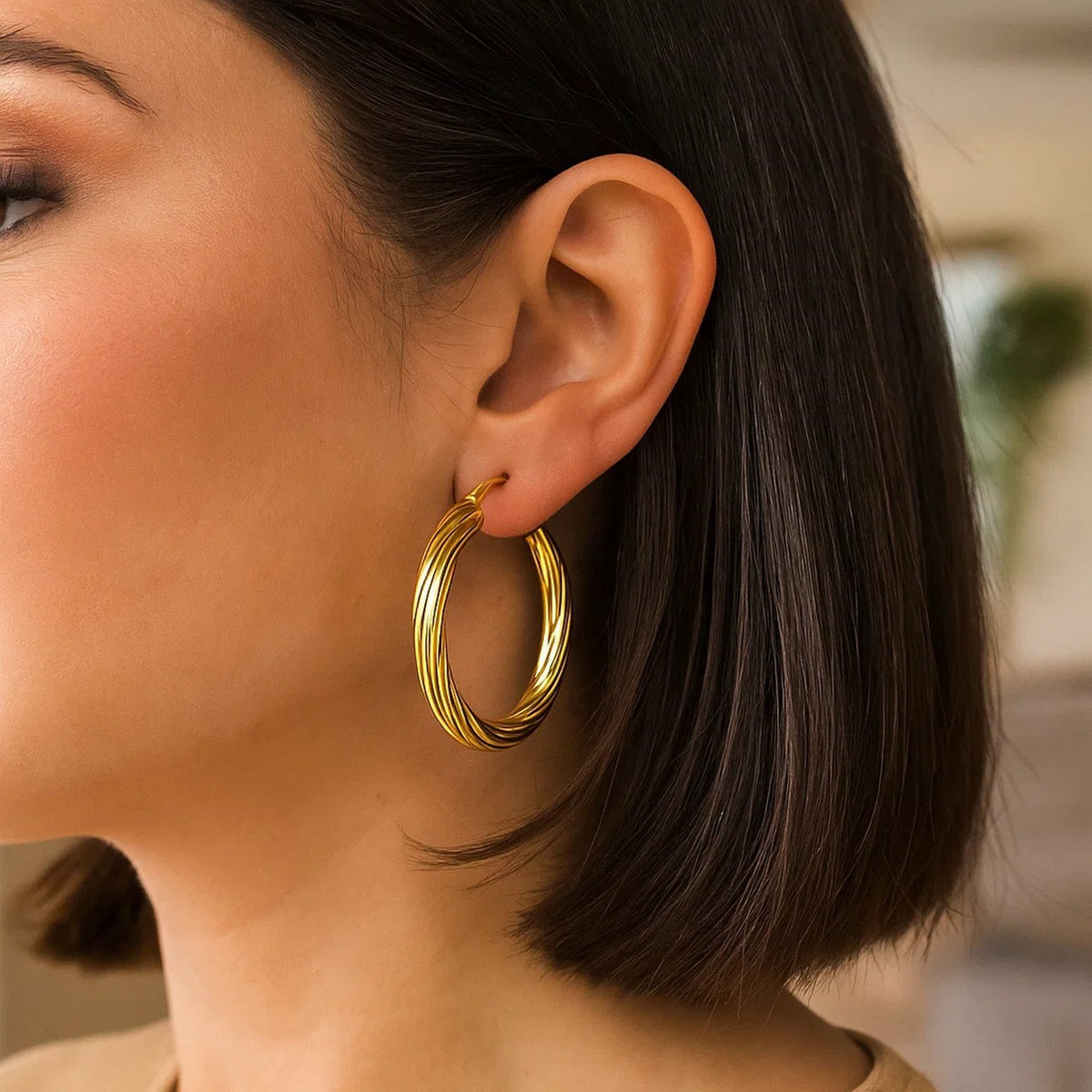 Large twisted 14K yellow gold hoop worn with a short bob