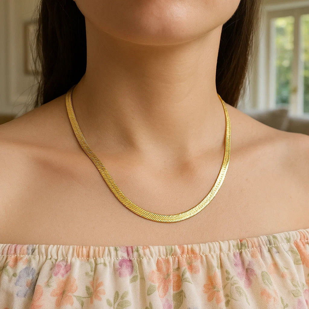 Herringbone chain in 14K yellow gold worn at the collarbone with a printed top