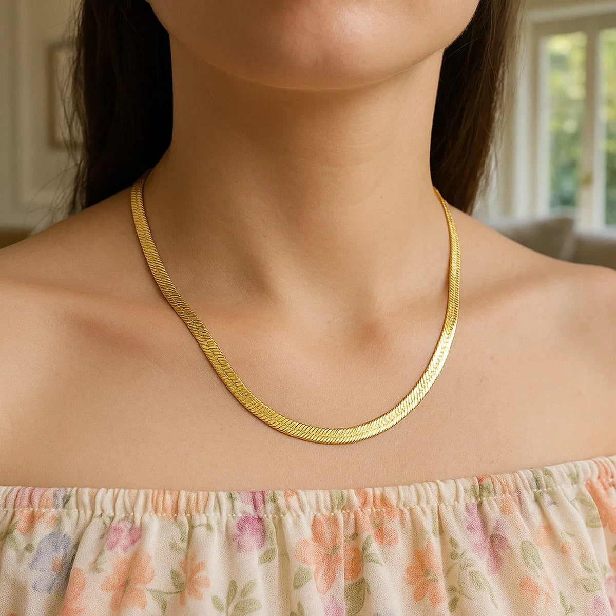 Herringbone chain in 14K yellow gold worn at the collarbone with a printed top