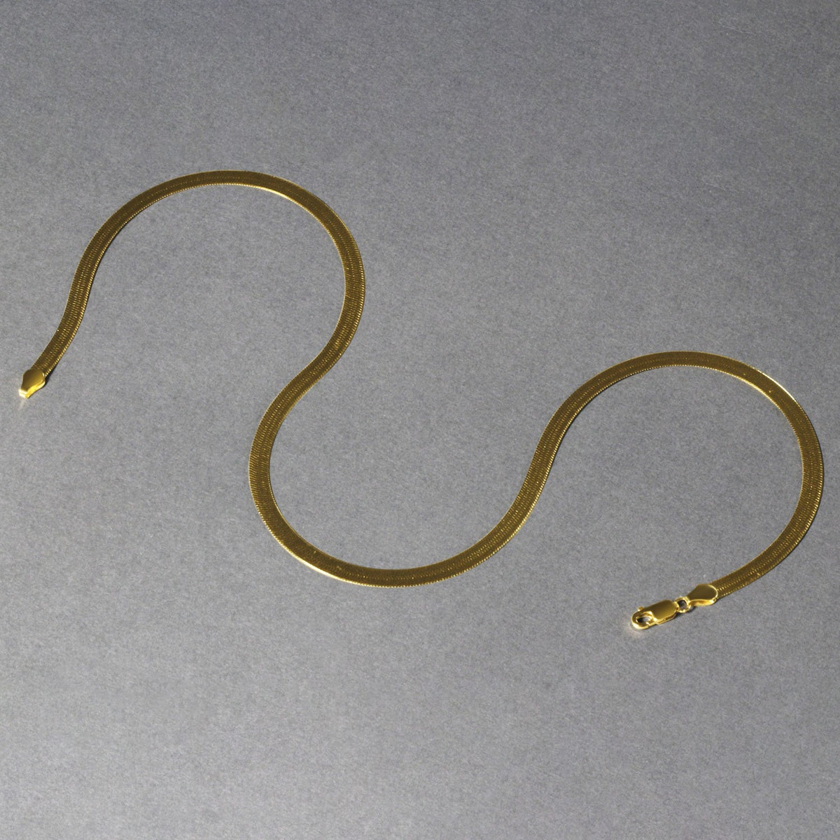 6.00mm herringbone chain in 14K yellow gold laid out in loops