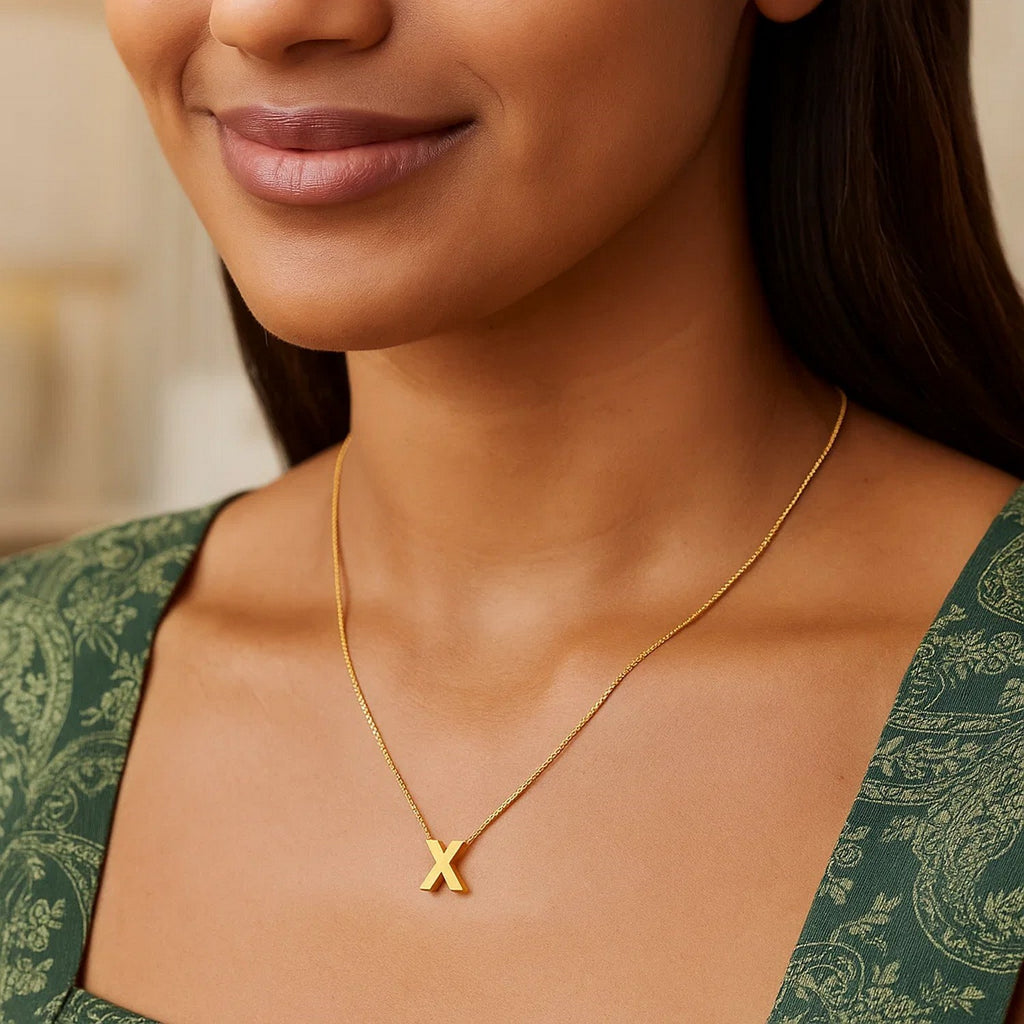 Block letter X initial necklace in 14K yellow gold worn at the neckline
