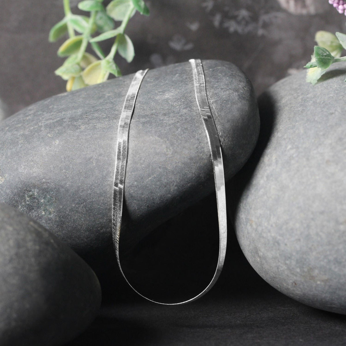 Herringbone chain in 14K white gold draped over two stones