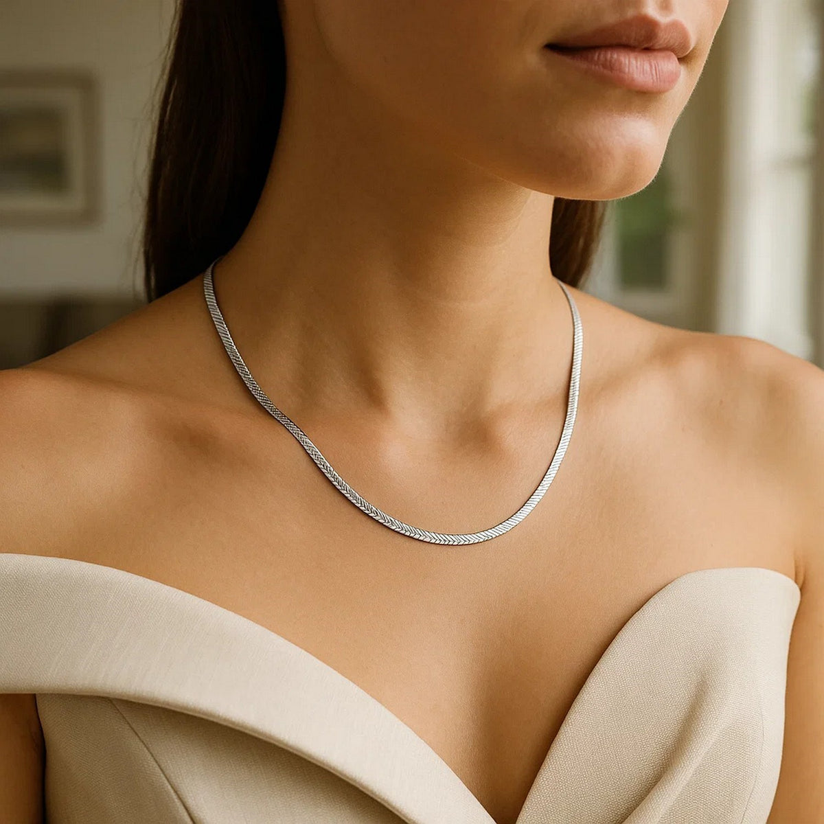 Herringbone chain in 14K white gold worn at the collarbone with an off-shoulder top