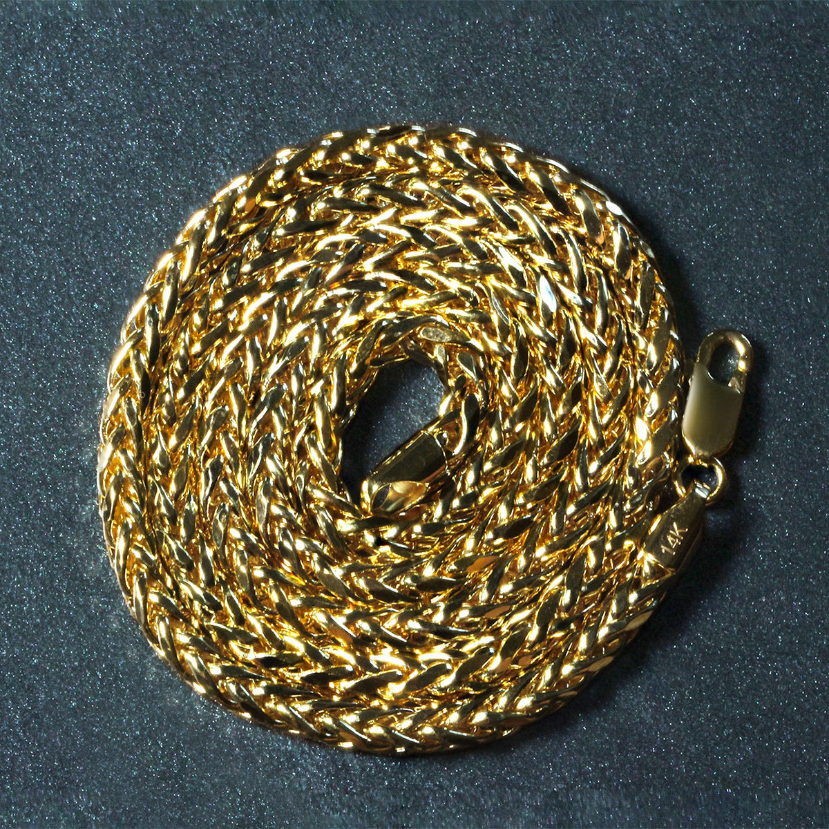 14K yellow gold Franco chain, 4.1mm, coiled on a dark surface